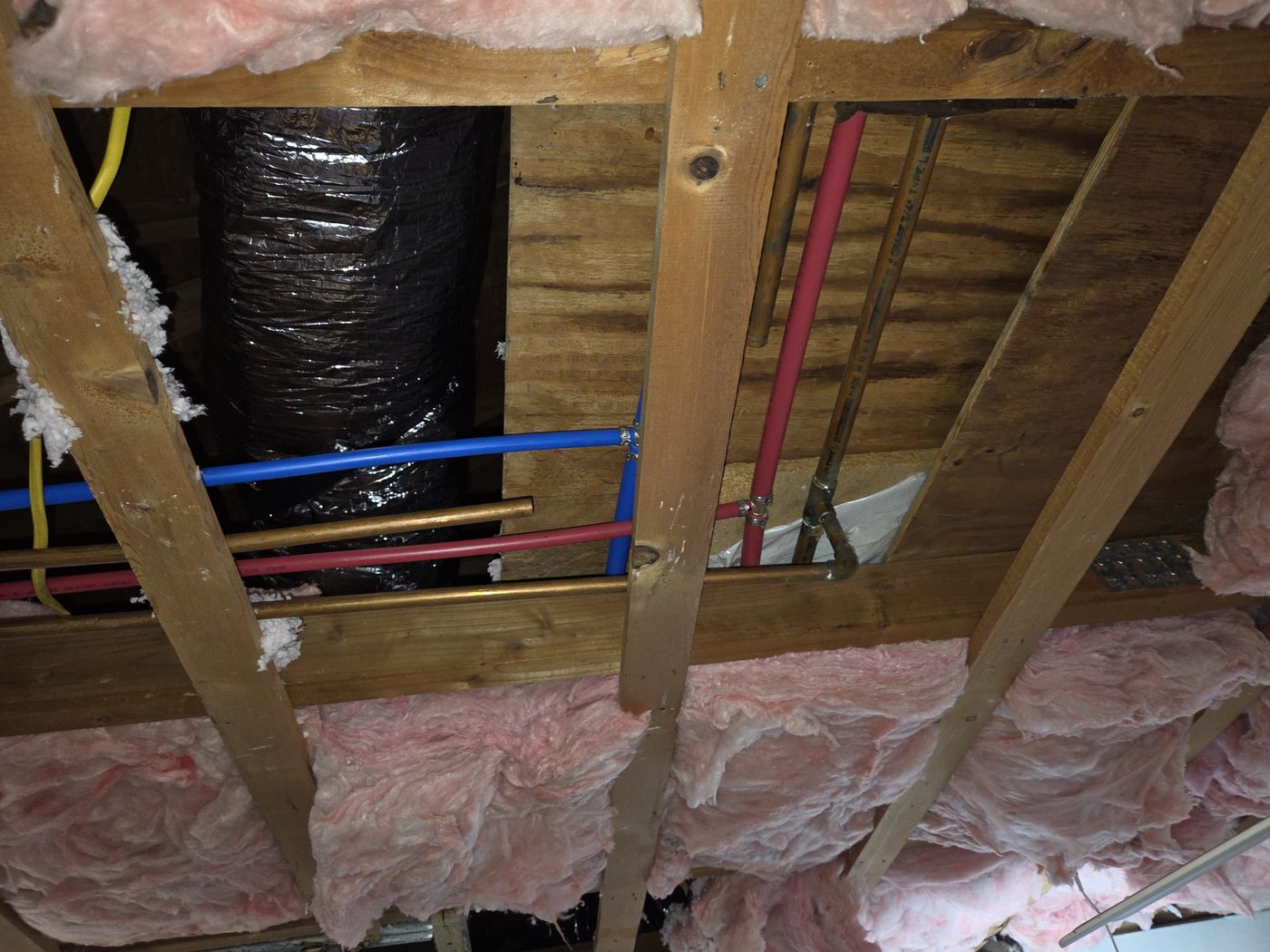 Ceiling opened in a 1971 Naples house showing original copper water lines beside newer PEX lines and a flex duct