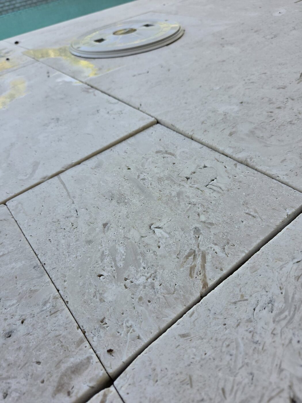 Uneven travertine pavers on a pool deck, a trip hazard on a new Naples home