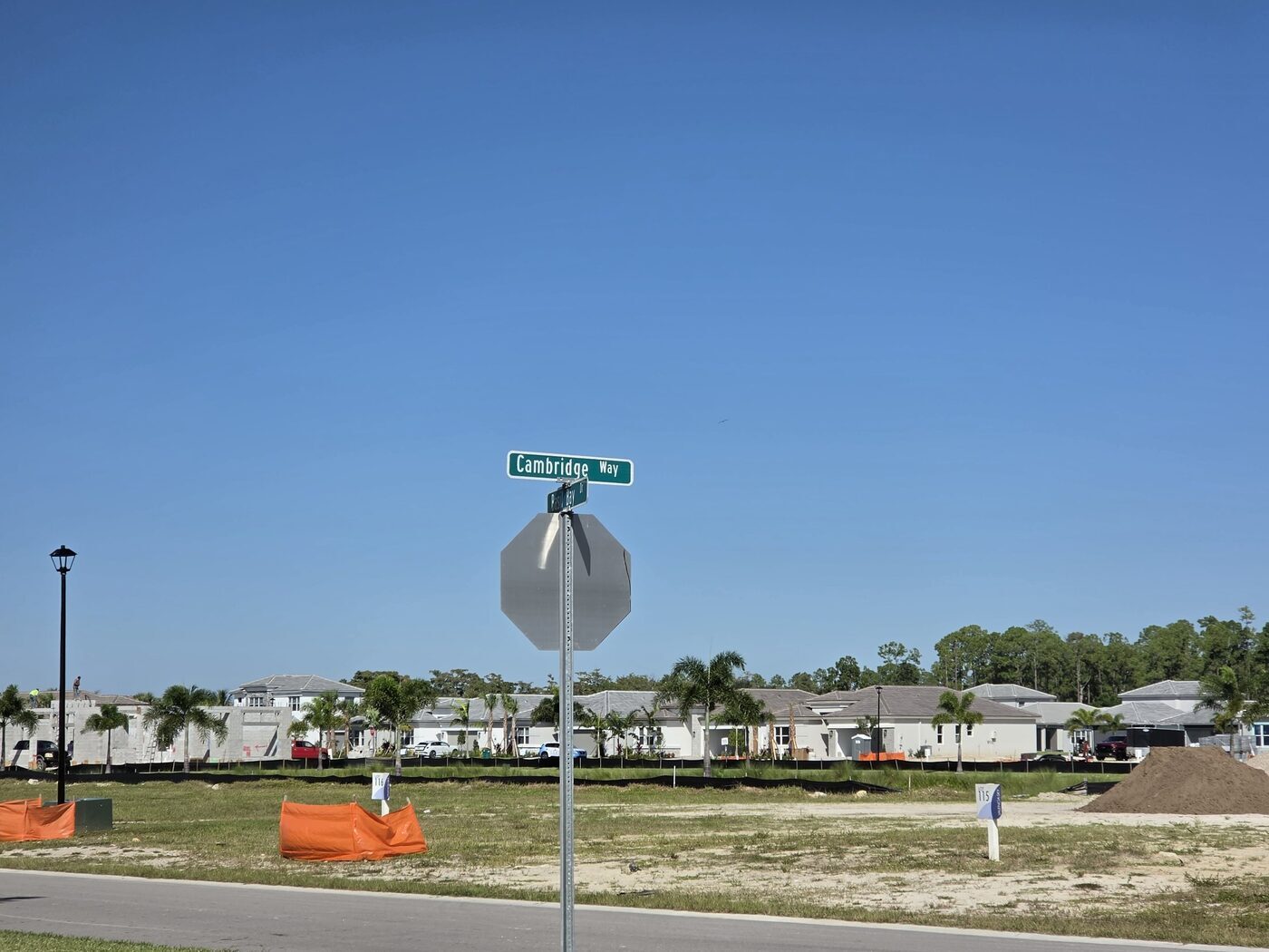 Cambridge Way street sign in Valencia Sky, Naples, with open lots in front and a row of finished homes behind